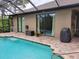 Backyard pool with brick surround, covered patio, and well-maintained landscaping at 142 Yellow Pine Dr, Rotonda West, FL 33947