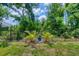 Well-maintained backyard featuring manicured lawn, mature trees, and decorative statue at 143 Crevalle Rd, Rotonda West, FL 33947