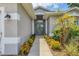 Close-up of the inviting front entrance, framed by colorful bushes and a gray facade at 143 Crevalle Rd, Rotonda West, FL 33947