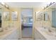 Bathroom with double vanity sinks, large mirrors, and decor leading to bedroom with queen bed at 1501 Beach Rd # 303, Englewood, FL 34223