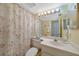 Well-lit bathroom featuring a vanity, mirror, toilet, and shower with floral curtain at 1501 Beach Rd # 303, Englewood, FL 34223