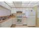 Compact kitchen with white appliances and cabinets, and tile flooring at 1501 Beach Rd # 303, Englewood, FL 34223