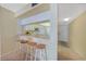 Eat-in kitchen with white cabinets, bar counter and four stools overlooking a tiled entry hallway at 1501 Beach Rd # 303, Englewood, FL 34223