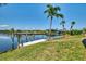Private boat dock with clear waterfront views surrounded by lush green lawn and a palm tree at 15020 Acorn Cir, Port Charlotte, FL 33981