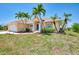 Desirable home showing lush lawn, red rock landscape, and mature palm trees in the front yard at 15020 Acorn Cir, Port Charlotte, FL 33981