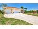 Spacious driveway and two-car garage are complemented by lush lawn and tropical landscaping at 15020 Acorn Cir, Port Charlotte, FL 33981