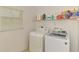 Bright laundry room featuring a washer, dryer, storage shelf, and a window at 15020 Acorn Cir, Port Charlotte, FL 33981