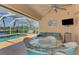 Inviting screened-in patio with comfortable seating, ceiling fan, and views of the pool and canal at 15020 Acorn Cir, Port Charlotte, FL 33981