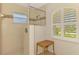 Shower with glass door and small window; a woven stool is placed next to the shower at 15020 Acorn Cir, Port Charlotte, FL 33981