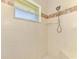 Bright, tiled shower with a built-in bench and showerhead, featuring a small window at 15020 Acorn Cir, Port Charlotte, FL 33981