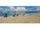 People relaxing on the beach with umbrellas, chairs, and a view of the tranquil, blue ocean at 1551 Beach Rd # 212, Englewood, FL 34223