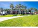 Three-story condo building with palm trees, balconies, and manicured lawn in a sunny, tropical setting at 1551 Beach Rd # 212, Englewood, FL 34223