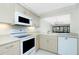 Open kitchen with light countertops, white appliances, and seamless transition to the living area with a balcony at 1551 Beach Rd # 212, Englewood, FL 34223