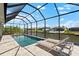 A beautiful waterfront pool with a screened-in enclosure and comfortable deck chairs offers a relaxing retreat at 15850 Viscount Cir, Port Charlotte, FL 33981