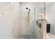 Close-up of marble tiled shower with rainfall shower head and built-in niche and pebble stone floor at 15850 Viscount Cir, Port Charlotte, FL 33981