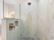 Close-up of shower head and marble tile featuring a built-in shower storage with pebble stone floor at 15850 Viscount Cir, Port Charlotte, FL 33981
