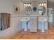 Charming bathroom featuring dual pedestal sinks, decorative tile, and warm terracotta flooring at 1605 Manor Rd, Englewood, FL 34223