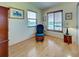 Bright office space with a comfortable blue chair, wood-look flooring, and natural light from two windows at 1605 Manor Rd, Englewood, FL 34223