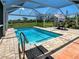 Inviting pool area with a clear blue swimming pool, caged enclosure, and outdoor dining set at 1605 Manor Rd, Englewood, FL 34223