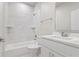 Well-lit bathroom featuring white marble tile, a tub, a toilet, and vanity with a quartz countertop at 1664 Karluk St, North Port, FL 34287