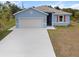 Charming single-story home with a two-car garage, light blue paint, and fresh landscaping at 1664 Karluk St, North Port, FL 34287