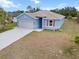 Inviting single-story home boasts a spacious driveway, light blue exterior paint and manicured lawn at 1664 Karluk St, North Port, FL 34287