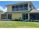 Exterior of yellow two-story home, boasting a screened balcony and lush yard at 169 Boundary Blvd # 169P, Rotonda West, FL 33947