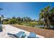 A spacious backyard features a lovely pond, blue lounge chairs, and lush tropical landscaping at 1691 Lakeview Pl, Englewood, FL 34223