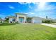 A beautiful, well-lit home featuring a manicured lawn and a two-car garage, complemented by tropical landscaping at 171 Mark Twain Ln, Rotonda West, FL 33947