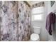 Cozy bathroom showing toilet, patterned shower curtain, and small window providing soft natural light at 1712 Fessler St, Englewood, FL 34223
