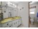 Bright bathroom featuring a vanity with gold countertops, a large mirror, and neutral tile flooring at 1712 Fessler St, Englewood, FL 34223