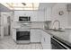 Well-lit kitchen featuring stainless steel appliances, white cabinets, and white tiled backsplash at 1712 Fessler St, Englewood, FL 34223
