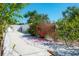 A well-manicured backyard with a white fence, red flowering shrubs, greenery, and a smooth paved path at 2060 Oyster Creek Dr, Englewood, FL 34224