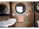 A stylish powder room features a modern sink, round mirrors, wood-look walls, and sleek fixtures at 2060 Oyster Creek Dr, Englewood, FL 34224