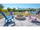 Backyard fire pit with colorful chairs and landscaping and a view of the waterfront and boat lift at 2060 Oyster Creek Dr, Englewood, FL 34224