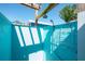 A refreshing turquoise-walled outdoor shower with a shower head, convenient storage rack, and dappled sunlight at 2060 Oyster Creek Dr, Englewood, FL 34224