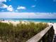 Scenic beach view with clear blue sky, turquoise water, and lush dune vegetation at 2117 Michigan Ave, Englewood, FL 34224