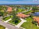 Stunning aerial view of a tile roof home on a manicured lot with a long driveway and lake view at 2692 Wax Myrtle Ct, Port Charlotte, FL 33953