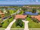 Beautiful aerial view of a home with tile roof, mature trees, lush green lawn, and a large driveway at 2692 Wax Myrtle Ct, Port Charlotte, FL 33953