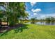 Expansive backyard lawn leading to a tranquil pond and featuring lush palm trees at 2692 Wax Myrtle Ct, Port Charlotte, FL 33953