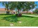 A lush green lawn and mature trees in front of a well-maintained home with a tiled roof at 2692 Wax Myrtle Ct, Port Charlotte, FL 33953
