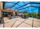 Spacious screened patio with tile flooring, outdoor seating and lush landscaping at 2692 Wax Myrtle Ct, Port Charlotte, FL 33953