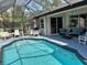 Sparkling swimming pool surrounded by a screened enclosure, patio, and lush landscaping at 2864 Traverse Ave, North Port, FL 34286