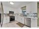 Well-lit kitchen featuring white cabinetry, stainless steel appliances, tile backsplash, and durable countertops at 3025 Curry Ter, Port Charlotte, FL 33981
