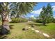 Landscaped backyard features lush grass, mature trees and a stepping stone path with rocks at 4510 Burns Ter, Port Charlotte, FL 33981