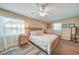 Comfortable bedroom featuring wood-look tile flooring, a ceiling fan, and sunlit windows at 4510 Burns Ter, Port Charlotte, FL 33981