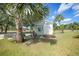 Outdoor storage shed featuring wooden ramp, landscaping, and mature palms on a grassy lot under a partly cloudy blue sky at 4510 Burns Ter, Port Charlotte, FL 33981