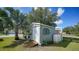Outbuilding featuring light blue siding, decorative windows, attached propane tanks, and lush lawn and landscaping at 4510 Burns Ter, Port Charlotte, FL 33981