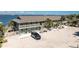 Two-story building featuring multiple units, surrounded by palm trees, water views and a car parked in the expansive parking area at 5041 N Beach Rd # 2A And 2B, Englewood, FL 34223