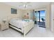 Bright main bedroom with white furniture, tile floors, and slider door leading to balcony with water view at 5041 N Beach Rd # 2A And 2B, Englewood, FL 34223